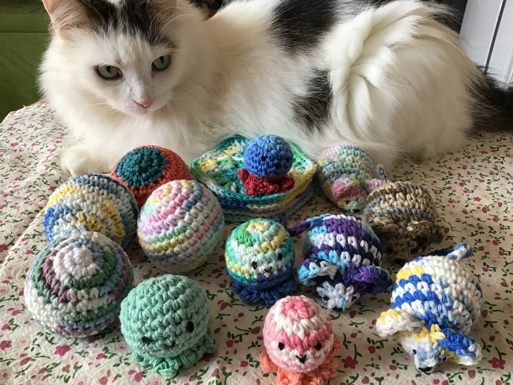 Kitty cat showing off a bunch of crochet kitty toys