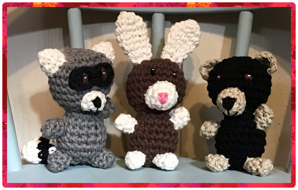Tiny stuffies sitting on a chair. Raccoon, rabbit, and black bear