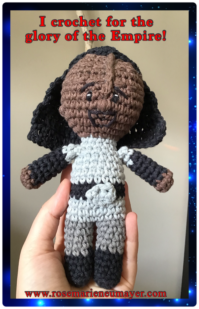 Hand holding up a Klingon stuffie doll in his warrior best. Text reads "I crochet for the glory of the empire!" And my website address