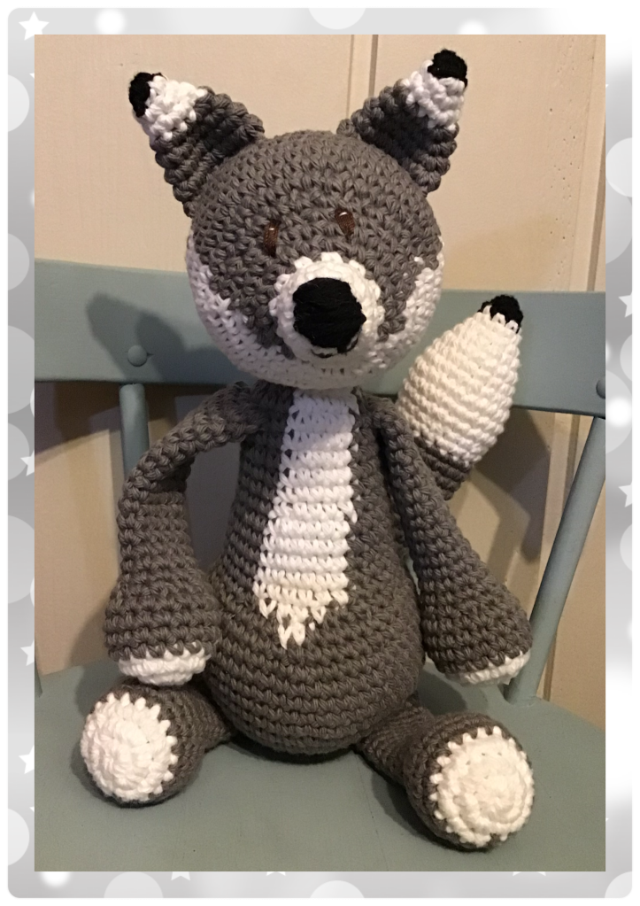 Grey wolf stuffie sitting on a wooden chair