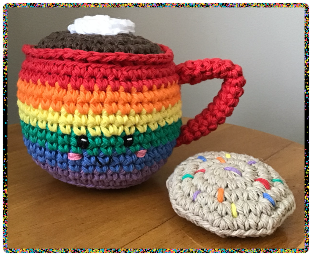 Mug and cookie stuffie set in rainbow colours sitting on a table
