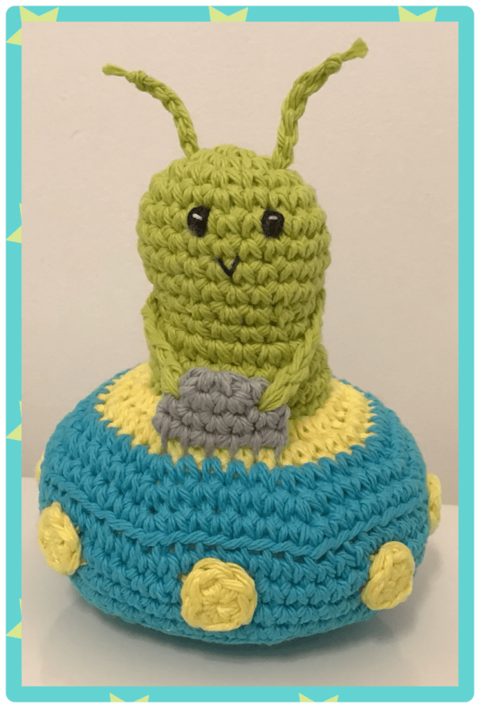 Alien in spaceship my own pattern. Alien is green and worm like sitting on a flying saucer