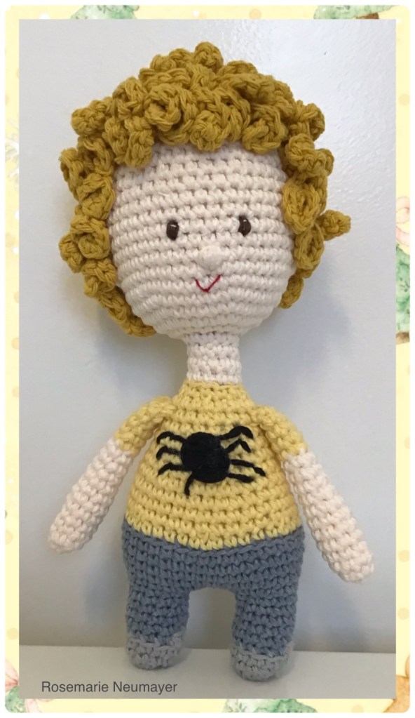 Boy doll in t-shirt and jeans. The boy is blond with curls and brown yeyes. His complexion is fair.