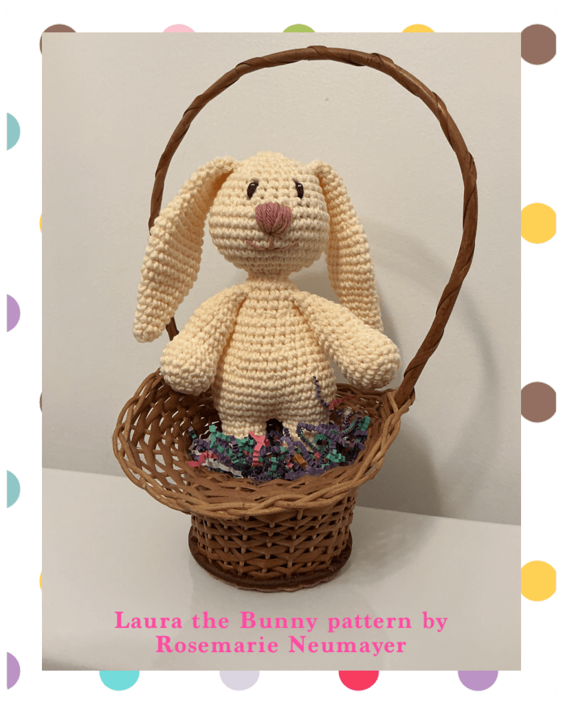 Picture of "Laura the Bunny" in a basket with basket grass. The picture has a border of colourful circles.